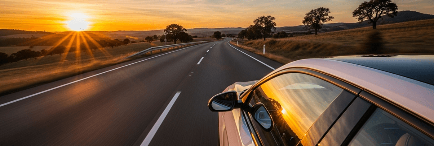 A car on a highway driving toward a sunset